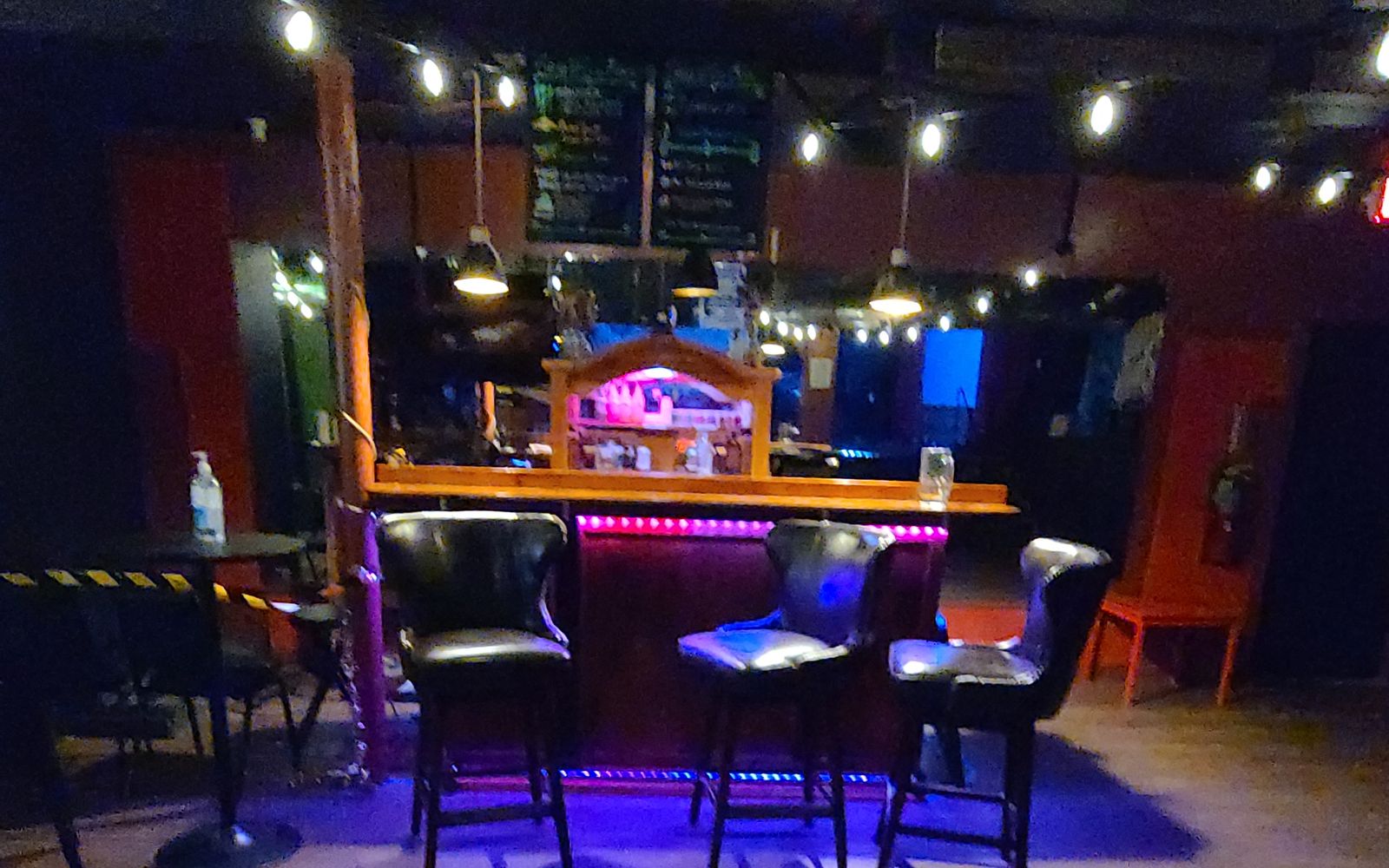 The downstairs bar today: leather stools, purple under-bar lights and string lights overhead